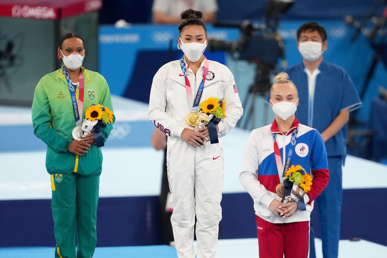 Gold medal winner Sunisa Lee of the United States, is flanked by silver medalist Rebeca Andrade of Brazil, left, and bronze medalist Angelina Melnikova of the Russian Olympic Committee during the medal ceremony for.the women's all-around gymnastics competition at the postponed 2020 Tokyo Olympics in Tokyo on Thursday, July 29, 2021. (Chang W. Lee/The New York Times)