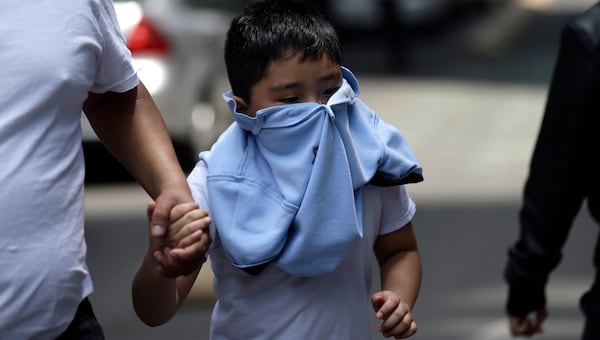 A boy with his face covered due to a gas leak holds aman's hand as people gather in Reforma Avenue after an earthquake in Mexico City, Tuesday Sept. 19, 2017. A powerful earthquake jolted central Mexico on Tuesday, causing buildings to sway sickeningly in the capital on the anniversary of a 1985 quake that did major damage.(AP Photo/Marco Ugarte)