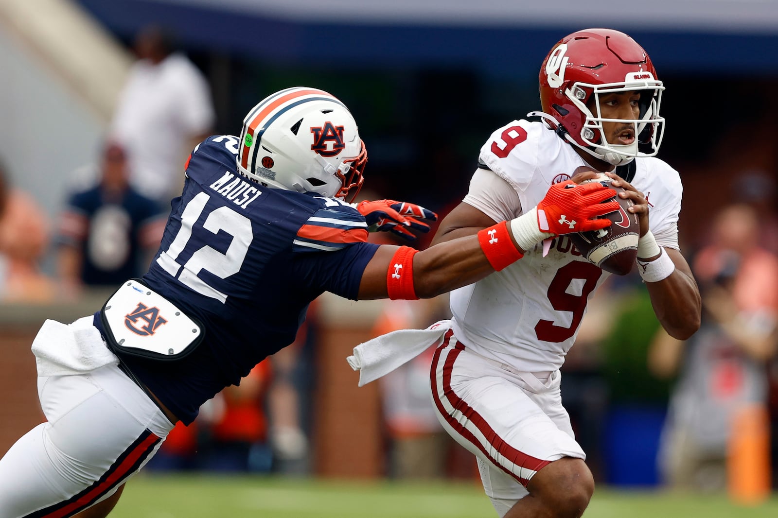 Oklahoma quarterback Michael Hawkins Jr. (9) escapes the pressure from Auburn linebacker Dorian Mausi Jr. (12) as he scrambles from the pocket during the first half of an NCAA college football game, Saturday, Sept. 28, 2024, in Auburn, Ala. (AP Photo/Butch Dill)