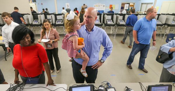 June 20, 2017 Sandy Springs: Neal Norris hold his daughter, Piper-1 as he waits for his registration to be confirmed on Tuesday, June 20, 2017at the Hammond Park Gymnasium at 705 Hammond Dr, Sandy Springs. Lots of money and lots of voters is what will be remembered about the nationally watched election to represent Atlantas northern suburbs in Congress, as 6th District voters choose whether to send Republican Karen Handel or Democrat Jon Ossoff to Washington. The district stretches from east Cobb to north DeKalb and the race is much more than a vote to fill out the remainder of former U.S. Rep. Tom Prices term after President Donald Trumps tapped him to be health secretary. Both parties have poured unprecedented resources into the race the cost now tops $50 million and both see it as a chance to send a message to the American electorate. Democrats hope an Ossoff victory could deal a blow to Trumps presidency and the GOP agenda, while giving other candidates a path toflipping more conservative strongholds. Republicans see a Handel win as a chance to bolster incumbents in competitive districts who are nervous about allying with Trump. JOHN SPINK/JSPINK@AJC.COM.