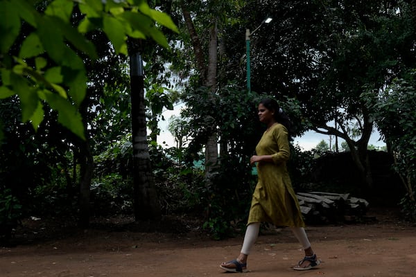 Shobha R, who works as a teacher at Swami Vivekananda Youth Movement, a nonprofit that works to help poor and Indigenous communities, walks past a solar light run by a refurbished lithium-ion batteries in Kenchanahalli, India, Monday, Sept. 23, 2024. (AP Photo/Aijaz Rahi)