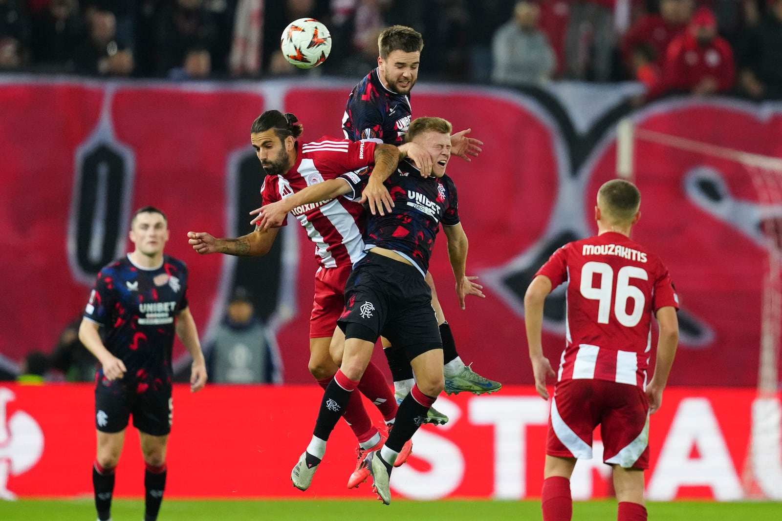 Olympiacos' Sergio Oliveira, left, jumps for the Baal among Rangers' Robin Proepper, centre and Connor Barron, right, during the Europa League opening phase soccer match between Olympiacos and Rangers at the Georgios Karaiskakis stadium at Athens' port of Piraeus, Greece, Thursday, Nov. 7, 2024. (AP Photo/Thanassis Stavrakis)