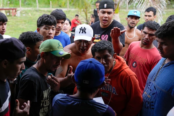 Venezuelan migrants discuss lodging and transit fees with a store owner in Puerto Cartí, on Panama's Caribbean coast, Saturday, Feb. 22, 2025, as they plan to board boats to Colombia after turning back from southern Mexico where they gave up hopes of reaching the U.S. amid President Trump's crackdown on migration. (AP Photo/Matias Delacroix)