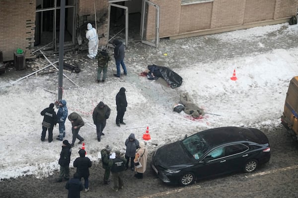 EDS NOTE: GRAPHIC CONTENT - Investigators work at the place where Lt. General Igor Kirillov, center, the head of Russia's Nuclear, Biological, and Chemical Defence Forces and his assistant, right, were killed by an explosive device planted close to a residential apartment's block in Moscow, Russia, Tuesday, Dec. 17, 2024. (AP Photo)