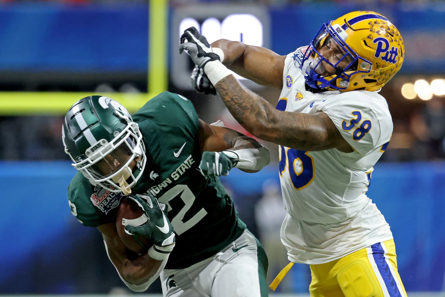 Pittsburgh Panthers linebacker Cam Bright (38) tackles Michigan State Spartans running back Harold Joiner (2) after a run during the first half of the Chick-fil-A Peach Bowl at Mercedes-Benz Stadium in Atlanta, Thursday, December 30, 2021. JASON GETZ FOR THE ATLANTA JOURNAL-CONSTITUTION