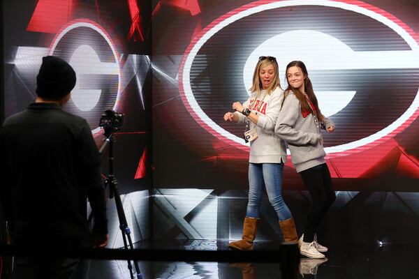 Deborah Lawler and her daughter Catelyn, 14, Athens, show off their moves in the Dance Party video booth while taking in the fan festival inside the Indianapolis Convention Center on Saturday, Jan. 8, 2022, in Indianapolis. The 200,000-square-foot interactive fan festival includes games, youth sports clinics, pep rallies and exhibits celebrating college football and its history.   “Curtis Compton / Curtis.Compton@ajc.com”`