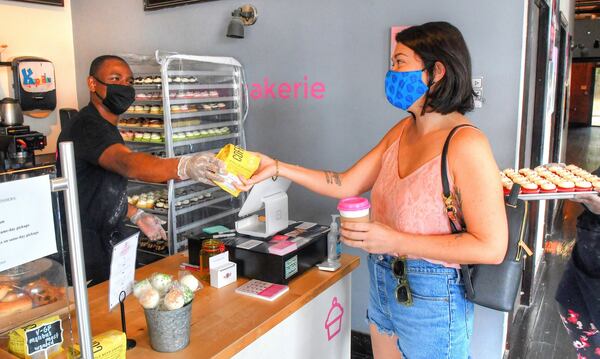 Henry Adeleye, co-owner of Kupcakerie on Main Street in downtown East Point, interacts with customer Katheryn Fitzgerald on a recent morning. Adeleye grew up in East Point. CONTRIBUTED BY CHRIS HUNT PHOTOGRAPHY