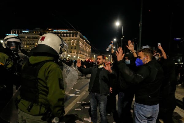 Protesters raise their hands as riot police operate during clashes, after the Greek opposition parties have challenged the country's center-right government with a censure motion in parliament over a devastating rail disaster nearly two years ago, in Athens, Wednesday, March 5, 2025. (AP Photo/Petros Giannakouris)