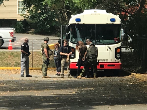 A couple of counterprotesters are detained near a bus on the square in Dahlonega on Saturday, Sept. 14, 2019. (Photo: Rosalind Bentley/AJC)