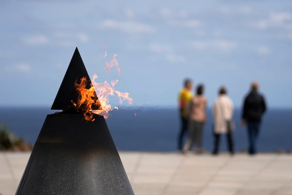 Visitors look at the Philippine Sea, standing near the Flame of Peace at the Cornerstone of Peace monument, created in memory of those who died in the Battle of Okinawa, at the Peace Memorial Park in Itoman, on the main island of the Okinawa archipelago, southern Japan, Friday, Feb. 14, 2025. (AP Photo/Hiro Komae)