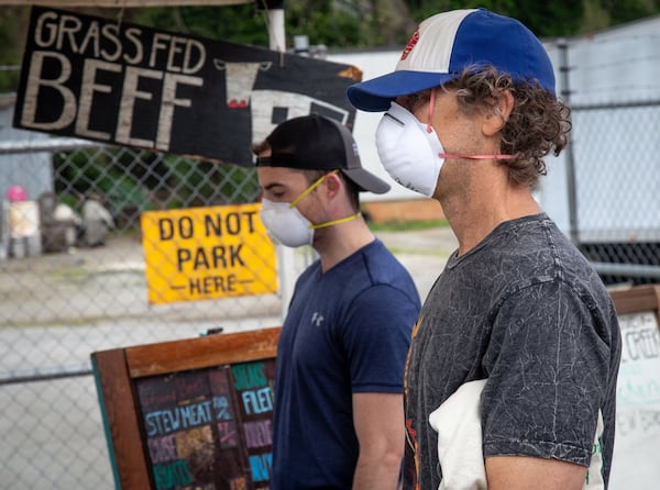 Kyle Senate (left) and Martin Gandy pick up some meat at the Pastures of Rose Creek’s booth at the Grant Park Farmers Market in Atlanta on March 29, 2020. STEVE SCHAEFER / SPECIAL TO THE AJC