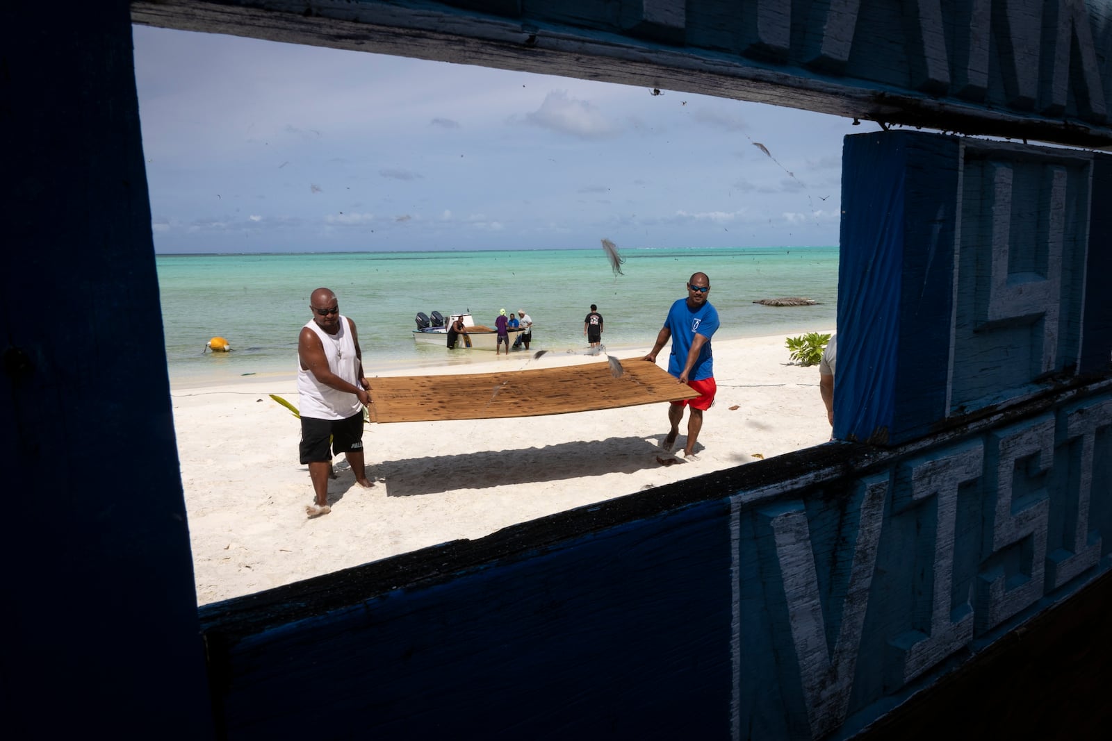 Brian Fidiiy and Ray Marino, the governor of Hatohobei State, carry lumber to the ranger station for maintenance repairs on Helen Island, Palau, July 17, 2024. (AP Photo/Yannick Peterhans)