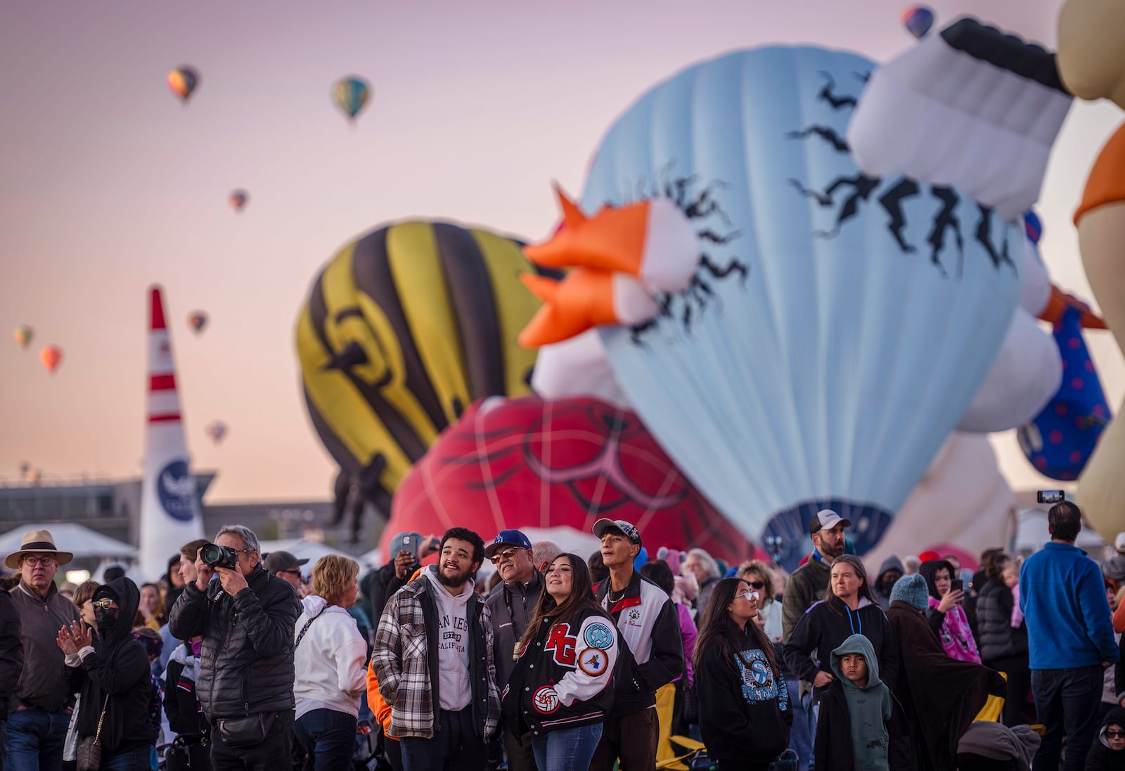 People view special shape balloons as they begin to inflate during the Albuquerque International Balloon Fiesta's Special Shape Rodeo and balloon launch at Balloon Fiesta Park in Albuquerque, N.M., on Thursday, Oct. 10, 2024. (Chancey Bush/The Albuquerque Journal via AP)