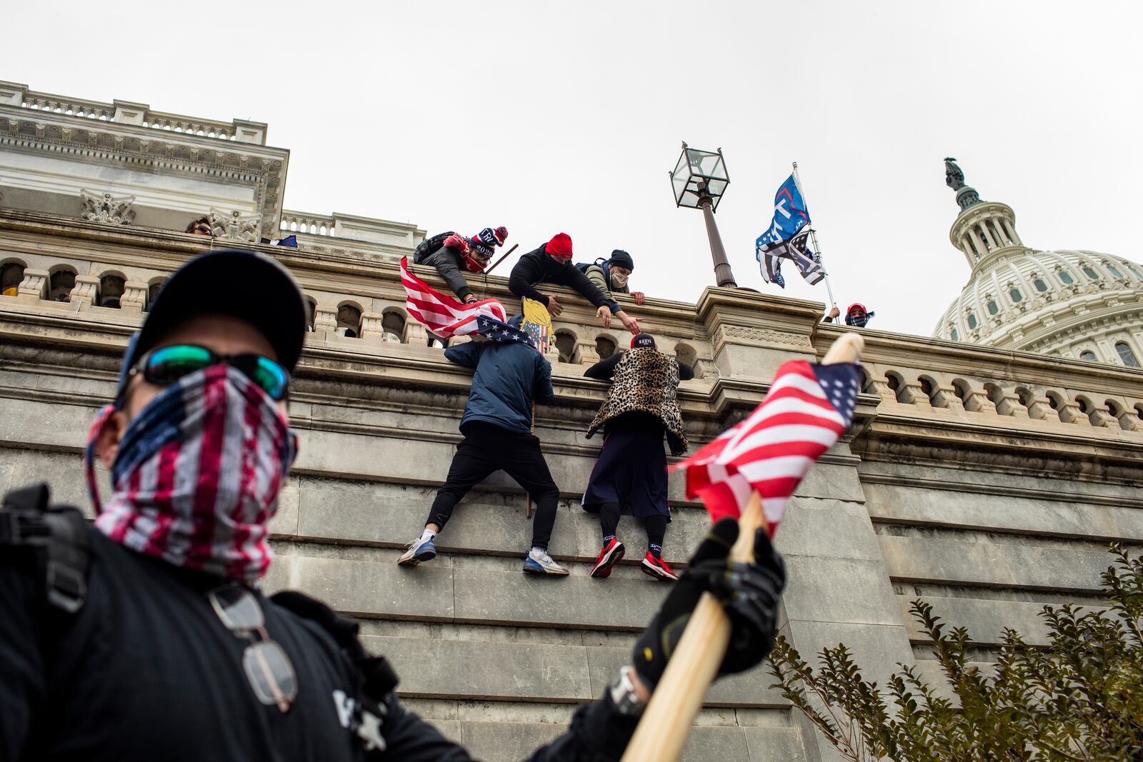 Protestors scale a wall of the U.S. Capitol in Washington on Jan. 6, 2021. A member of the far-right Proud Boys was texting with his FBI handler during the assault, but maintained the group had no plan in advance to enter the Capitol and disrupt the election certification. 