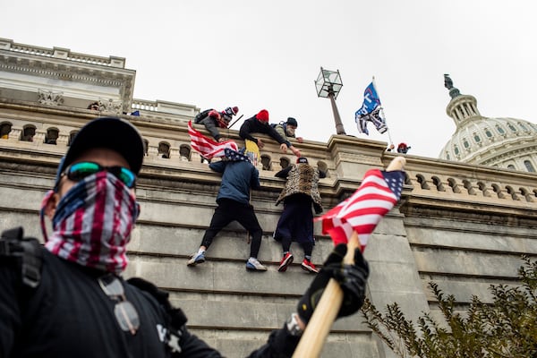 Protestors scale a wall of the U.S. Capitol in Washington on Jan. 6, 2021. A member of the far-right Proud Boys was texting with his FBI handler during the assault, but maintained the group had no plan in advance to enter the Capitol and disrupt the election certification. 