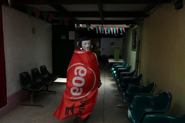 A voter wrapped in a flag of the Frente Amplio (Broad Front) arrives to a polling station to vote in the presidential run-off in Montevideo, Uruguay, Sunday, Nov. 24, 2024. (AP Photo/Matilde Campodonico)