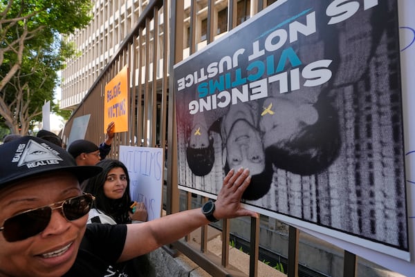 Supporters place signs on a fence outside of the Clara Shortridge Foltz Criminal Justice Center during a press conference regarding developments in the Menendez brothers case Thursday, March 20, 2025, in Los Angeles. (AP Photo/Damian Dovarganes)