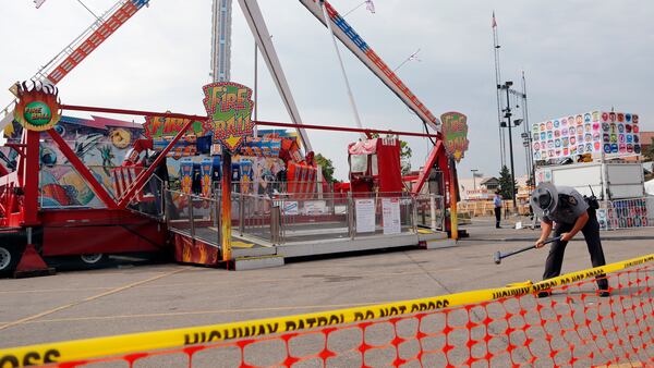 An Ohio State Highway Patrol trooper removes a ground spike from in front of the fire ball ride at the Ohio State Fair Thursday, July 27, 2017, in Columbus, Ohio.  The fair opened Thursday but its amusement rides remained closed one day after Tyler Jarrell, 18, was killed and seven other people were injured when the thrill ride broke apart and flung people into the air. (AP Photo/Jay LaPrete)