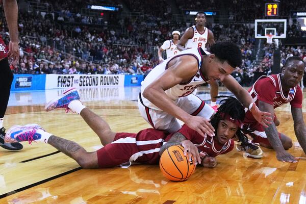 Arkansas forward Jonas Aidoo, bottom, drops to the floor to chase a loose ball against St. John's guard RJ Luis Jr. during the first half in the second round of the NCAA college basketball tournament, Saturday, March 22, 2025, in Providence, R.I. (AP Photo/Charles Krupa)