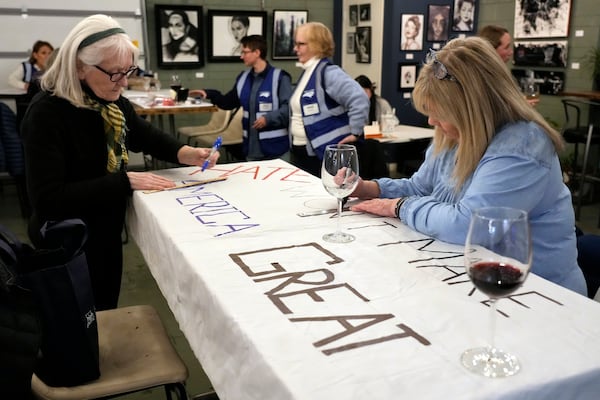 Ann Kourelis, left, and Candee Minchin, right, work on a protest sign during a meeting of NC Forward in High Point, N.C., Tuesday, Jan. 14, 2025. The group is traveling to Washington to take part in the People's March on Jan. 18 ahead of the inauguration. (AP Photo/Chuck Burton)