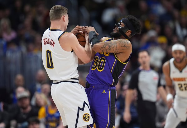 Los Angeles Lakers guard Jordan Goodwin, right, wrestles control of a loose ball away from Denver Nuggets guard Christian Braun in the first half of an NBA basketball game Saturday, Feb. 22, 2025, in Denver. (AP Photo/David Zalubowski)