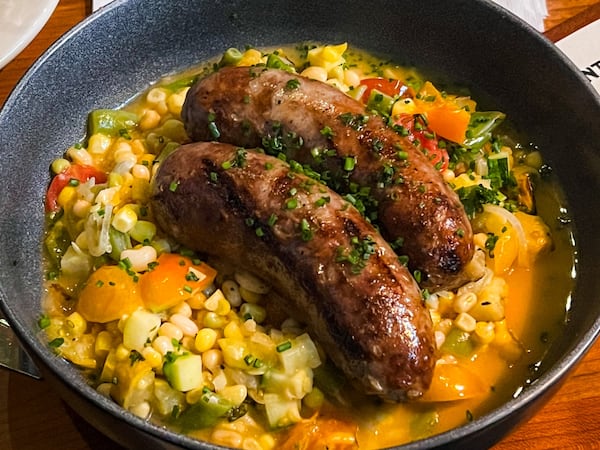 The Porter makes its own sausage, including the red wine and garlic sausage, served here over summer succotash. (Henri Hollis/henri.hollis@ajc.com)