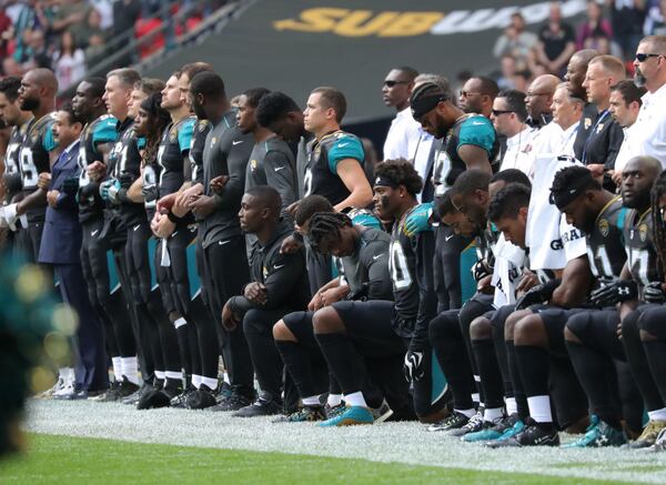 Jacksonville Jaguars Owner Shahid Kahn links arms with his team as some players take a knee during the National Anthem during the NFL match between the Jacksonville Jaguars and the Baltimore Ravens on September 24, 2017. (Photo by Mitchell Gunn/Getty Images)