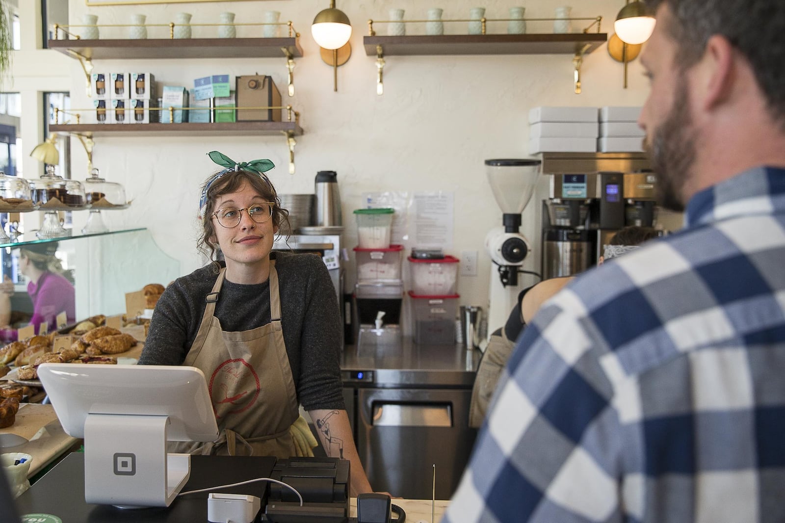 Little Tart Bakeshop employee Amy Gregg, left, works with a customer at the bakery in the Summerhill community. 