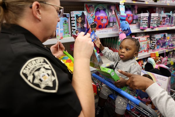 15-month-old Mahogani Thomas shops for toys with Lieutenant Melissa Shaw at Walmart, Tuesday, December 13, 2022, in Canton, Ga. Not pictured is Queen Thomas, Mahogani’s mother. The child was shopping with the Cherokee County Deputies during their annual ‘Christmas Joy’ event to buy toys for underprivileged children. (Jason Getz / Jason.Getz@ajc.com)