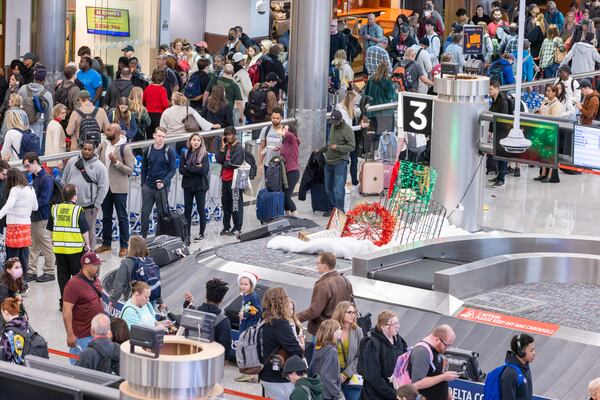 Travelers wait in long lines that stretch to the baggage pickup at the domestic terminal of Hartsfield-Jackson airport in Atlanta on Tuesday, December 26, 2023, the day after Christmas. (Arvin Temkar / arvin.temkar@ajc.com)