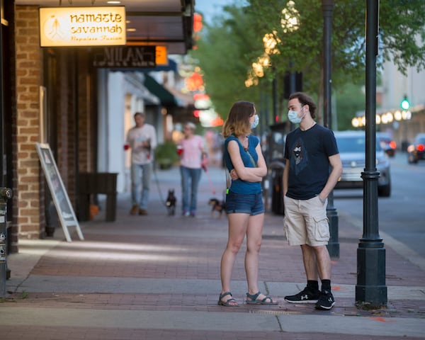 Wearing masks for protection from the coronavirus, two Savannah College of Art and Design students wait for their takeout order at a restaurant on Broughton Street in the city's historic downtown. (AJC Photo/Stephen B. Morton)