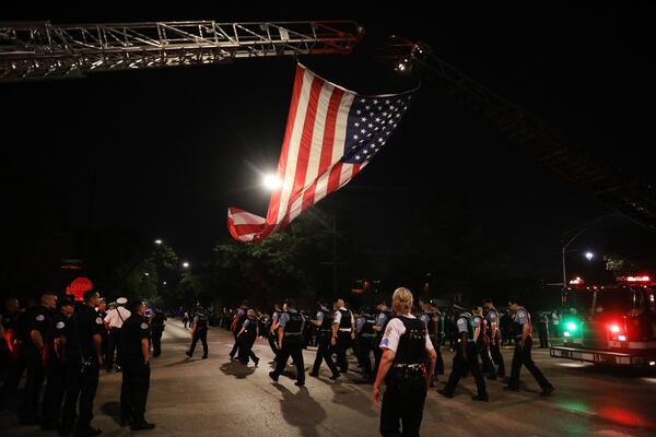 Chicago police officers walk under a giant U.S. flag prior to an ambulance carrying the body of a fellow officer arriving at the Cook County Medical Examiner's Office early Sunday.