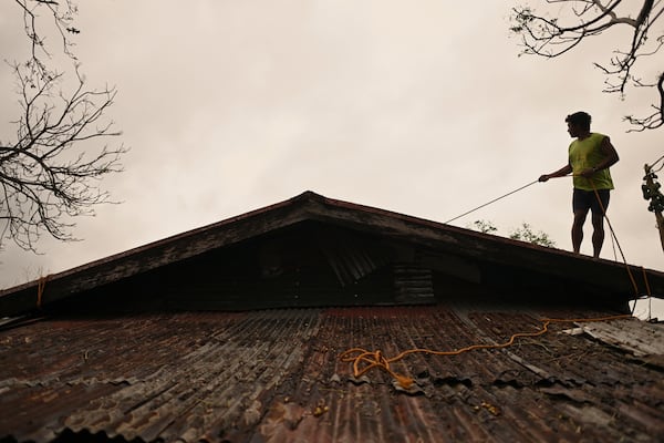 A resident reinforces the roof of their house in Santa Ana, Cagayan Province, northern Philippines as they anticipate Typhoon Usagi to hit their area Thursday, Nov. 14, 2024. (AP Photo/Noel Celis)