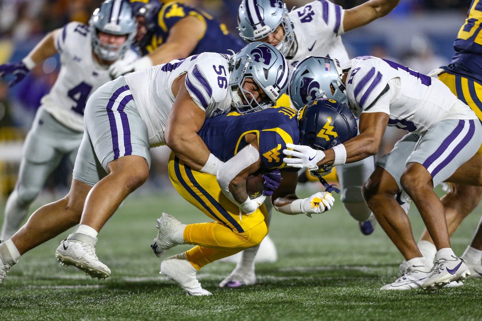 West Virginia running back Jahiem White (1) is tackled by Kansas State defensive tackle Damian Ilalio (56) and cornerback Jacob Parrish (10)during the frist half of an NCAA college football game, Saturday, Oct. 19, 2024, in Morgantown, W.Va. (AP Photo/William Wotring)