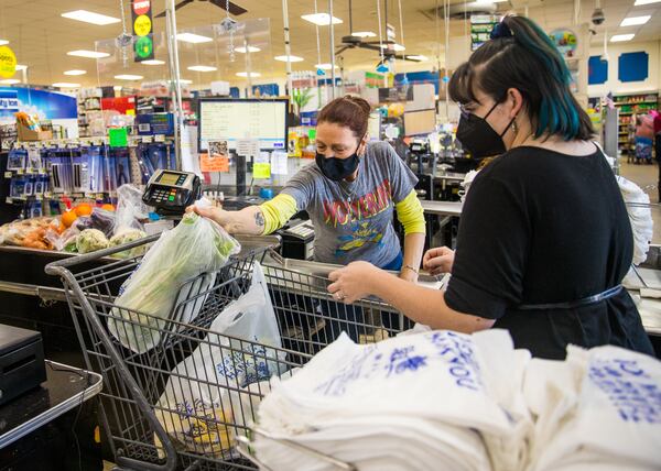 China Myrick of New American Pathways, right, checks out with cashier Martha Brown, left, at Clarkston Thriftown. Myrick was shopping for a family of five arriving from Afghanistan (Jenni Girtman for The Atlanta Journal-Constitution) 