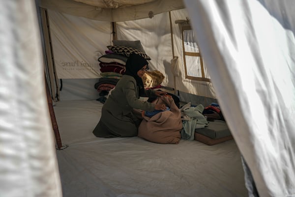 Majida Abu Jarad packs belongings as she prepares to go back to the family's home in the north, at a camp for displaced Palestinians in the Muwasi area, southern Gaza Strip, Saturday, Jan. 18, 2025. (AP Photo/Abdel Kareem Hana)