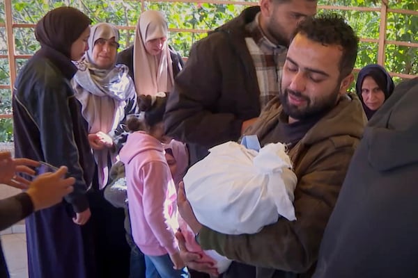 In this image made from an Associated Press video, Alaa Abu Helal holds the body of his 13-month-old son, Mohammed, before Mohammed and his pregnant mother, Afana, were buried in Khan Younis, Gaza Strip, Wednesday, March 19, 2025. They were killed before dawn Tuesday by an Israeli airstrike. (AP Photo/Mohammad Jahjouh)