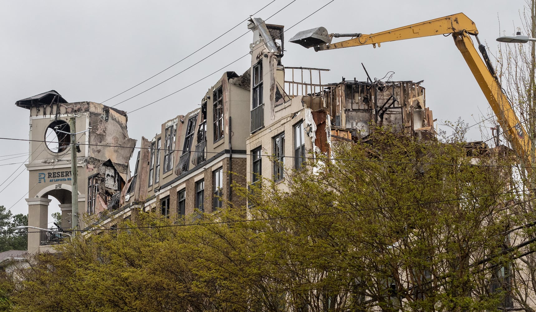 Contractors began tearing down the crumbling building that went up in flames in November this week with plans to open the road in front of the complex by Monday. (Photo by John Spink/AJC)