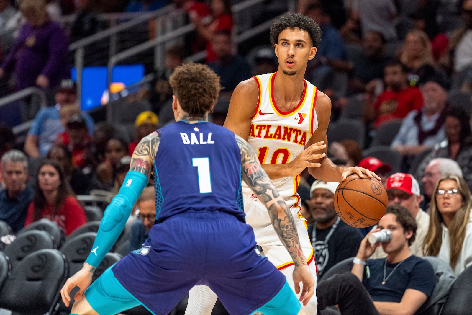 Atlanta Hawks forward Zaccharie Risacher (10) looks for an open teammate while guarded by Charlotte Hornets guard LaMelo Ball (1) during the first half of an NBA basketball game, Friday, Oct. 25, 2024, in Atlanta. (AP Photo/Jason Allen)