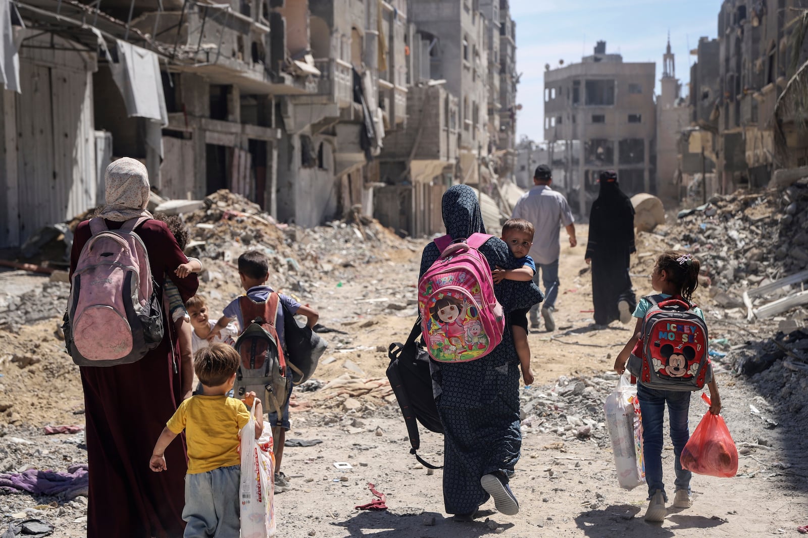 FILE - Palestinian women and their children walk though destruction in the wake of an Israeli air and ground offensive in Jebaliya, northern Gaza Strip after Israeli forces withdrew from the area, on May 31, 2024. (AP Photo/Enas Rami)