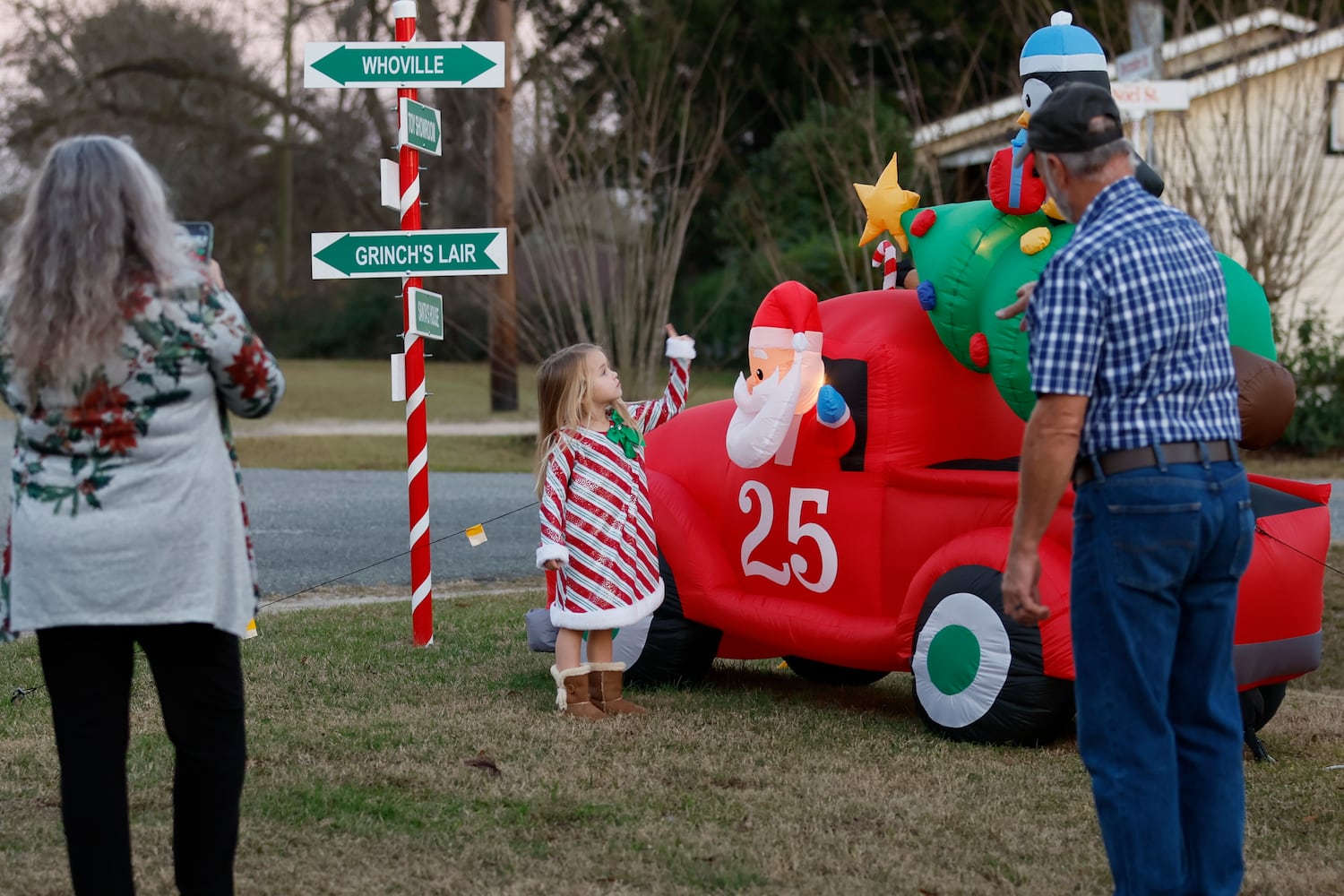 Santa Claus City council member Renee Wright tries to take a photo of her granddaughter Alayna Jernigan as her husband, Walter Wright, looks at one of the intersections decorated with candy cane stripes and inflatable decorations.
 Miguel Martinez / miguel.martinezjimenez@ajc.com