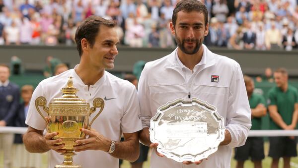 Switzerland's Roger Federer, left, holds the winners trophy alongside Croatia's Marin Cilic with the runners up plate, after the Men's Singles final match on day thirteen at the Wimbledon Tennis Championships in London Sunday, July 16, 2017.