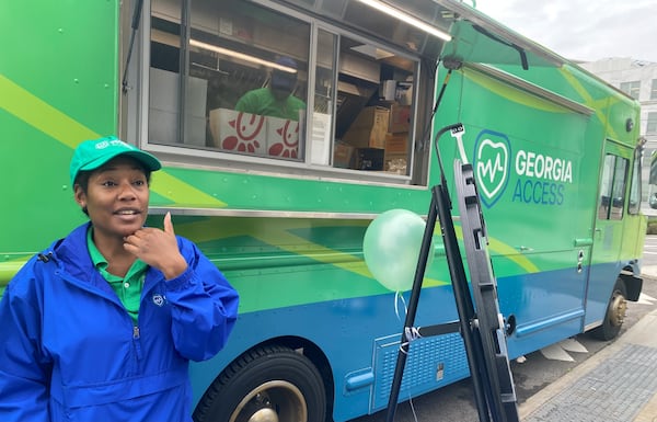 GeorgiaAccess.gov outreach workers like Sheena Wiley were hired to travel the state and hand out promotional materials for people who might be eligible to get health insurance on the state's new Affordable Care Act website. The truck behind Wiley serves tea and coffee. They took part in the Georgia Access launch event Friday, Nov. 1, 2024 near the Georgia Capitol. Georgia Access is the new state-based exchange marketplace for the Affordable Care Act in Georgia, run by the office of Insurance Commissioner John King. (Photo by Ariel Hart)