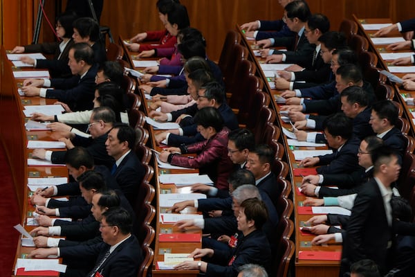 Chinese delegates press buttons to vote during the closing ceremony of the National People's Congress held at the Great Hall of the People in Beijing, Tuesday, March 11, 2025. (AP Photo/Ng Han Guan)