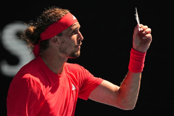 Alexander Zverev of Germany reacts as he holds a feather during his quarterfinal match against Tommy Paul of the U.S. during their quarterfinal match at the Australian Open tennis championship in Melbourne, Australia, Tuesday, Jan. 21, 2025. (AP Photo/Vincent Thian)