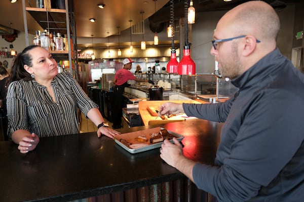 Jessica Mosie, general manager of Twin Smokers BBQ, and Matthew Youhess, director of food and beverage for Legacy Ventures restaurants, sample the day’s smoked meats prior to the lunch rush Friday, Jan. 17, 2025. Legacy Ventures restaurants include Max’s Coal Oven Pizzeria, StatsBrewpub, Twin Smokers BBQ and Der Biergarten in downtown Atlanta.  Ben Gray for the Atlanta Journal-Constitution