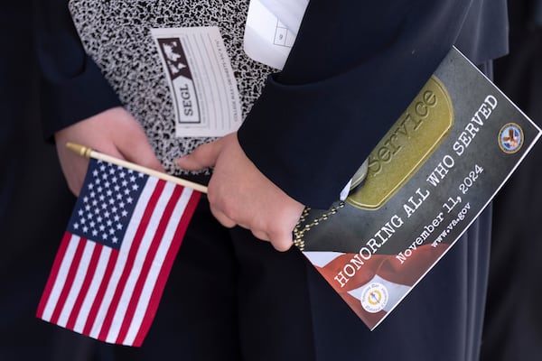 A person holds a flag as they attend the National Veterans Day Observance at the Memorial Amphitheater at Arlington National Cemetery in Arlington, Va., Monday, Nov. 11, 2024. (AP Photo/Ben Curtis)