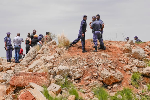 Police officers and volunteer rescuers stand by the opening of a reformed gold mineshaft where illegal miners are trapped in Stilfontein, South Africa, Friday, Nov. 15, 2024. (AP Photo/Denis Farrell)