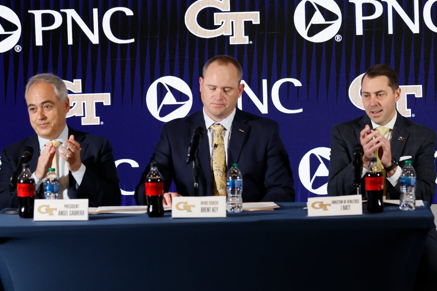 Georgia Tech President Ángel Cabrera (left) and athletic director J Batt (right) applaud as they introduce the new football head football coach Brent Key during a news conference on Monday, Dec. 5, 2022.
 Miguel Martinez / miguel.martinezjimenez@ajc.com