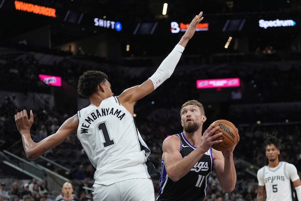 Sacramento Kings forward Domantas Sabonis (11) looks to shoot against San Antonio Spurs center Victor Wembanyama (1) during the first half of an NBA basketball game in San Antonio, Monday, Nov. 11, 2024. (AP Photo/Eric Gay)